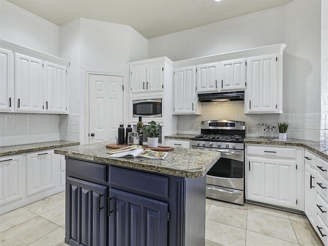 kitchen featuring white cabinetry, appliances with stainless steel finishes, decorative backsplash, dark stone counters, and a kitchen island