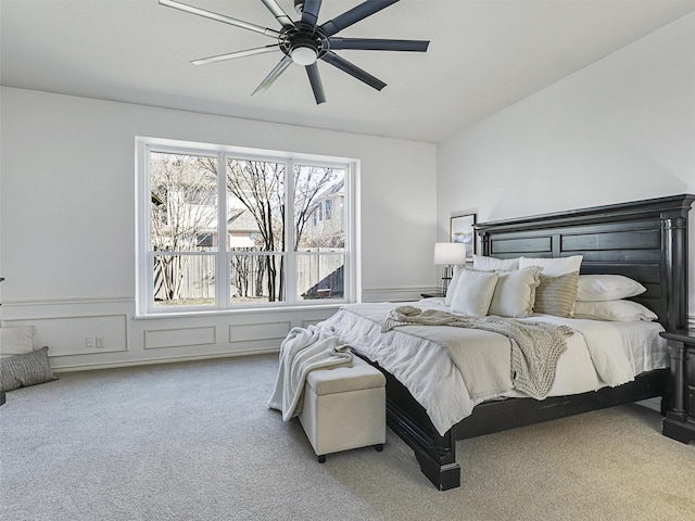 bedroom featuring wainscoting, carpet, ceiling fan, and a decorative wall