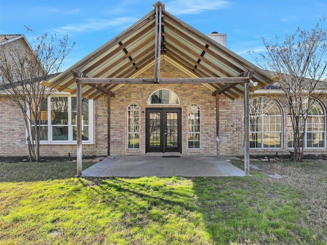 back of house with a patio, french doors, a lawn, and brick siding