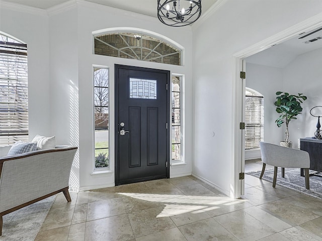 entryway featuring baseboards, ornamental molding, and an inviting chandelier