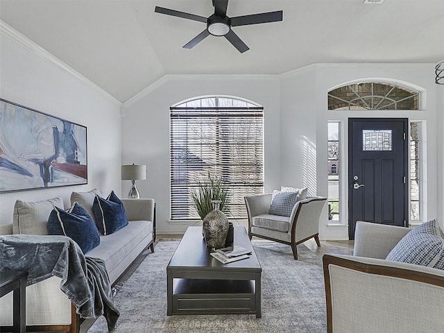 living area featuring lofted ceiling, ornamental molding, and a ceiling fan