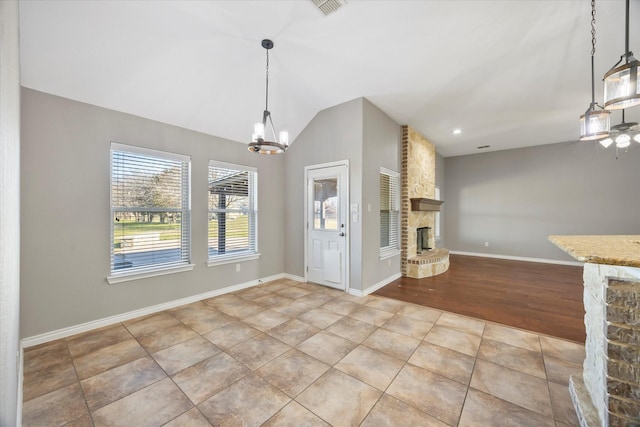 interior space with vaulted ceiling, an inviting chandelier, a fireplace, and decorative light fixtures