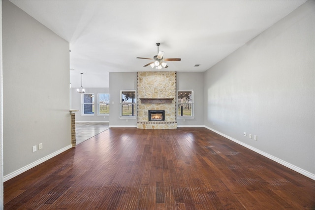 unfurnished living room featuring dark wood-type flooring, a fireplace, and ceiling fan with notable chandelier