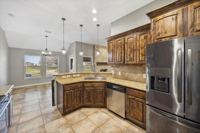 kitchen featuring stainless steel appliances, decorative backsplash, hanging light fixtures, light stone countertops, and sink