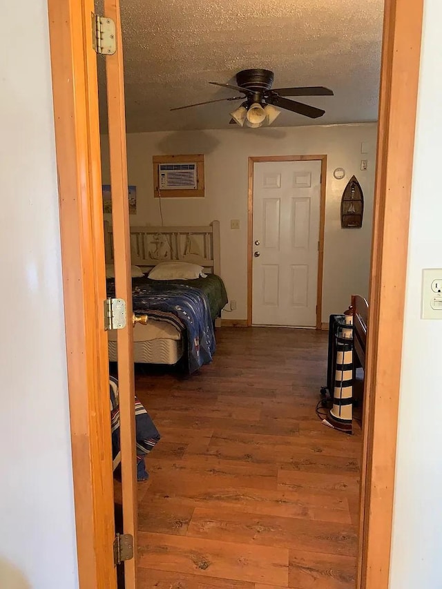 bedroom with ceiling fan, a wall mounted AC, a textured ceiling, and hardwood / wood-style floors