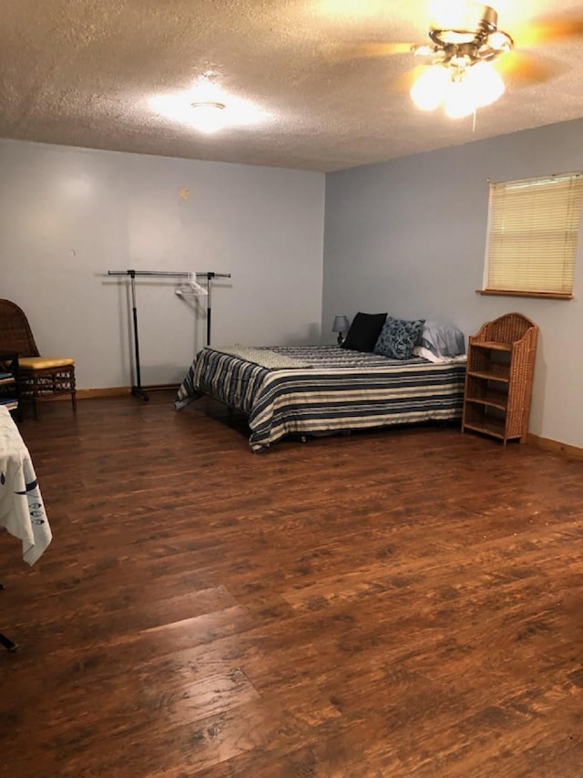 bedroom with ceiling fan, dark hardwood / wood-style floors, and a textured ceiling