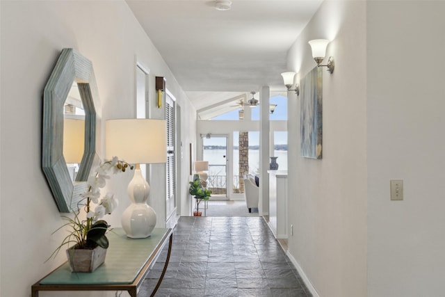 hallway featuring a water view and lofted ceiling