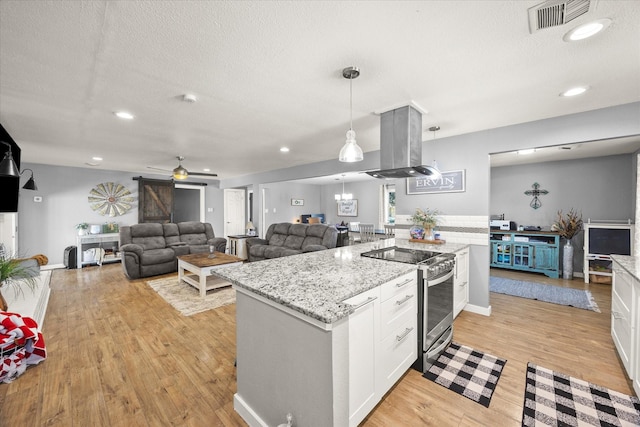 kitchen featuring a barn door, pendant lighting, island exhaust hood, stainless steel electric range oven, and white cabinets