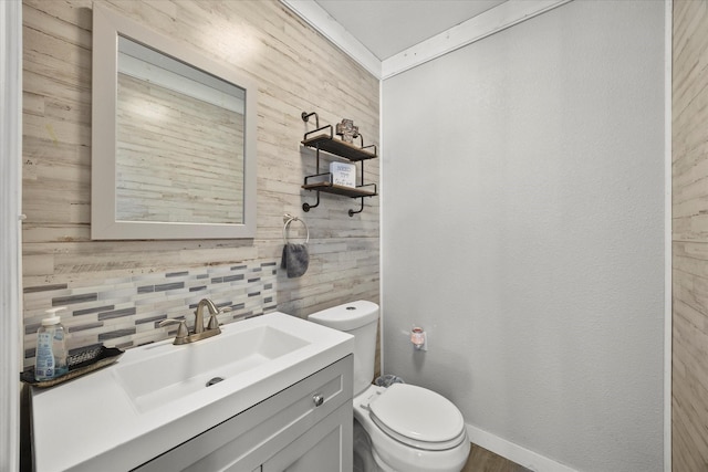 bathroom with toilet, vanity, backsplash, and crown molding