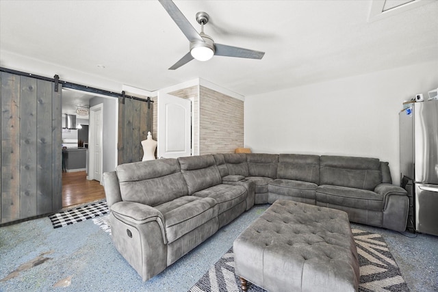 living room featuring ceiling fan and a barn door