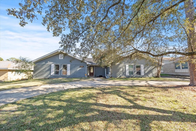view of front of home with driveway, brick siding, and a front yard
