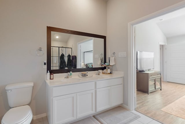 bathroom with tile patterned floors, vanity, toilet, and vaulted ceiling