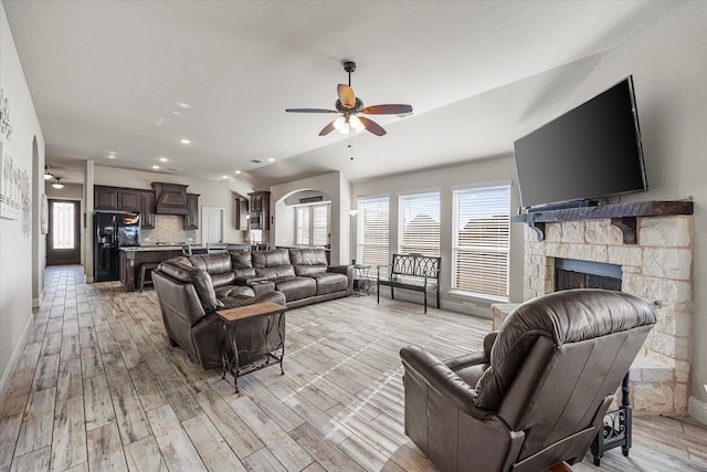 living area with baseboards, ceiling fan, a wealth of natural light, and light wood-style flooring