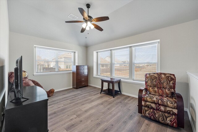 living area featuring ceiling fan, baseboards, wood finished floors, lofted ceiling, and visible vents
