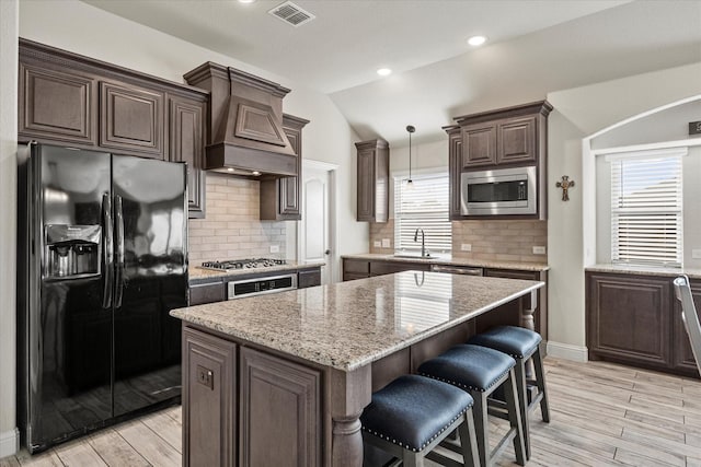 kitchen featuring appliances with stainless steel finishes, a center island, lofted ceiling, sink, and hanging light fixtures