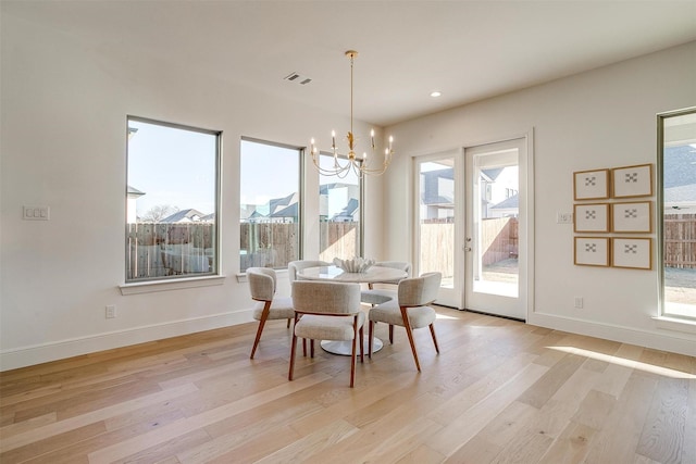 dining area with light wood-type flooring and a notable chandelier