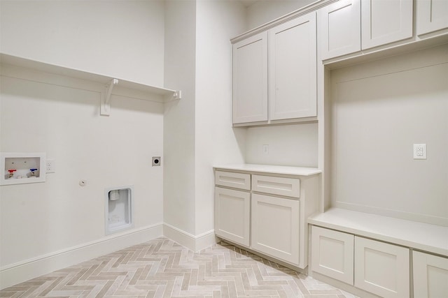 clothes washing area featuring light parquet floors, washer hookup, hookup for an electric dryer, gas dryer hookup, and cabinets