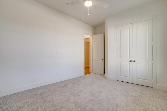 unfurnished bedroom with ceiling fan, light colored carpet, and a closet