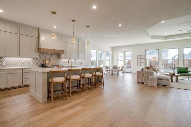 kitchen with hanging light fixtures, a breakfast bar, light hardwood / wood-style flooring, and a center island with sink