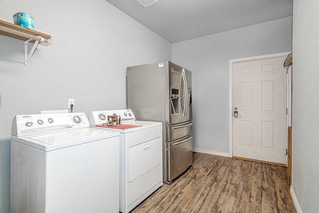 clothes washing area with hardwood / wood-style flooring and washer and dryer