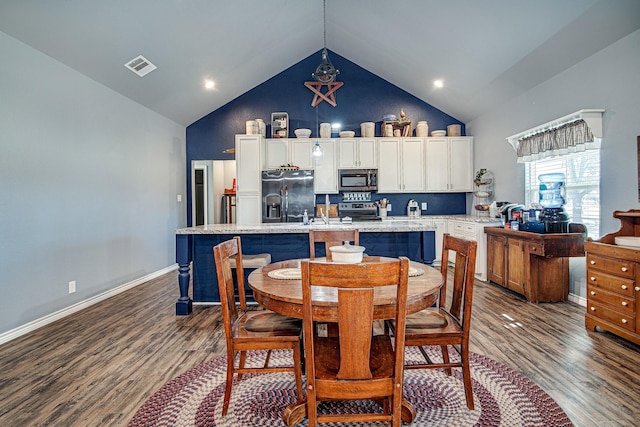 dining space featuring dark wood-type flooring and high vaulted ceiling