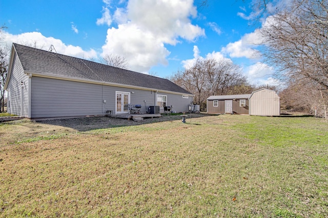 back of property with central AC, a lawn, french doors, and a shed