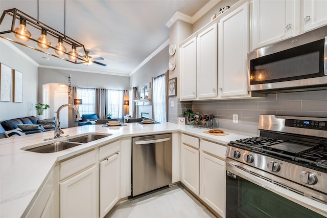 kitchen featuring tasteful backsplash, open floor plan, decorative light fixtures, stainless steel appliances, and a sink