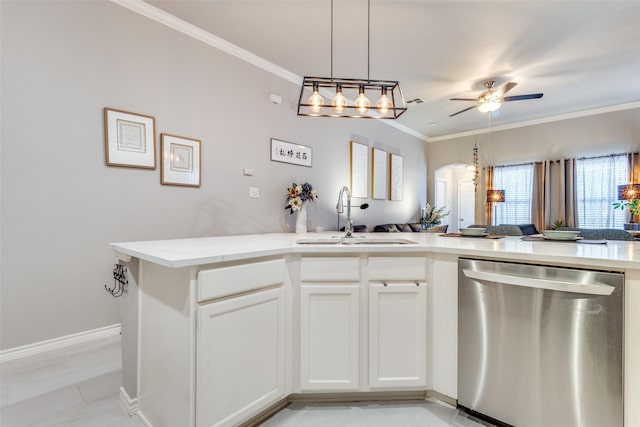 kitchen with arched walkways, white cabinets, light countertops, stainless steel dishwasher, and a sink