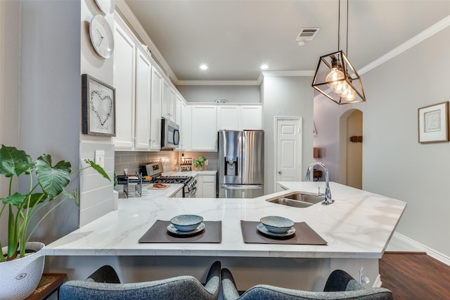 kitchen with a sink, white cabinetry, appliances with stainless steel finishes, decorative backsplash, and pendant lighting