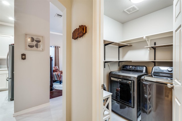 washroom featuring laundry area, visible vents, washer and clothes dryer, and arched walkways