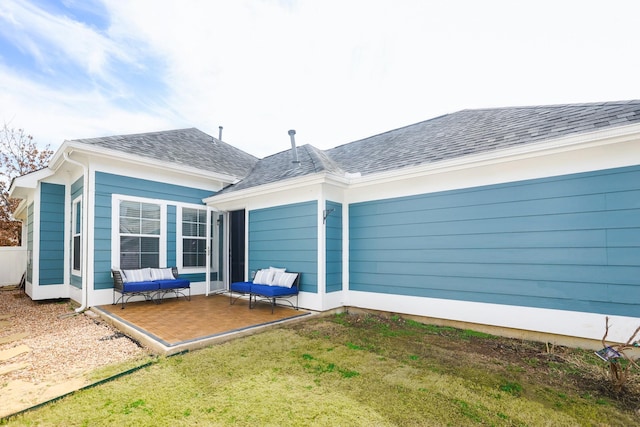 back of house featuring a shingled roof, a patio area, and a yard