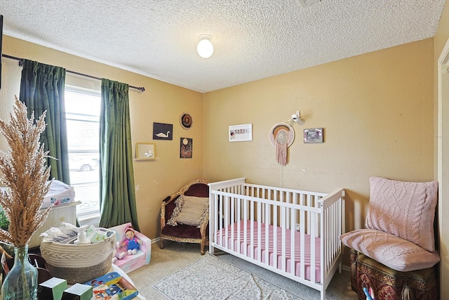 carpeted bedroom featuring a textured ceiling and a crib