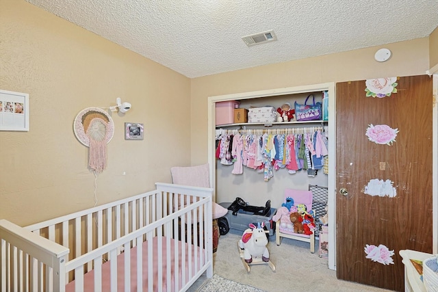 carpeted bedroom featuring a textured ceiling and a crib