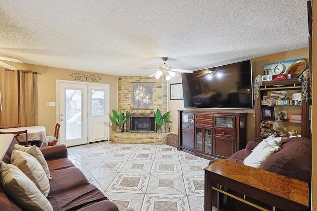 living room with a textured ceiling, ceiling fan, and a fireplace