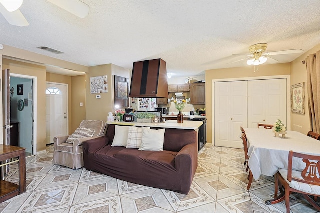 living room with ceiling fan and a textured ceiling