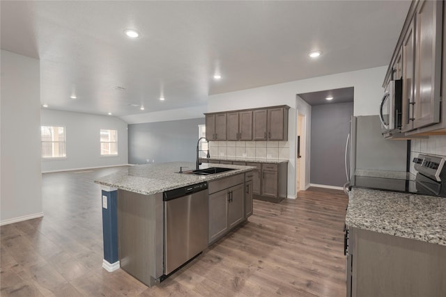 kitchen with a sink, tasteful backsplash, appliances with stainless steel finishes, and wood finished floors