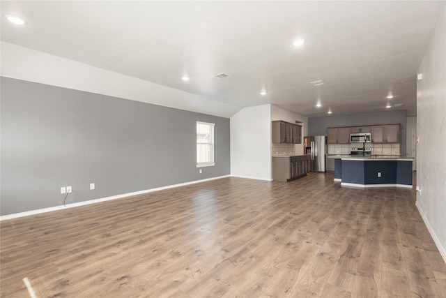 unfurnished living room featuring wood finished floors, visible vents, and baseboards