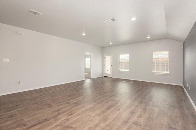 spare room with visible vents, baseboards, dark wood-style flooring, and vaulted ceiling