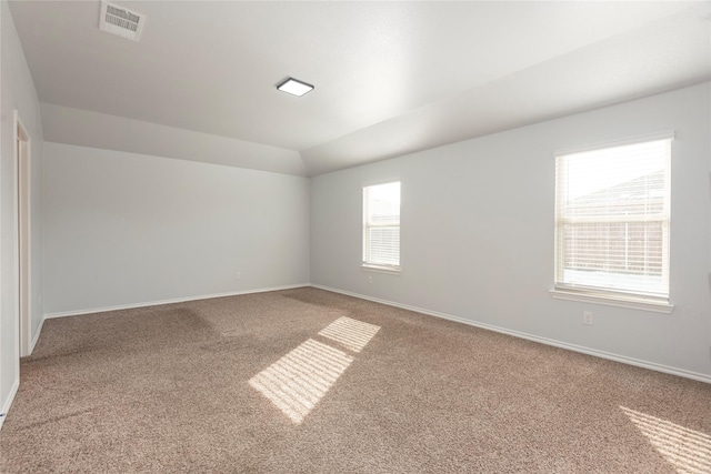 spare room with visible vents, carpet floors, baseboards, and vaulted ceiling