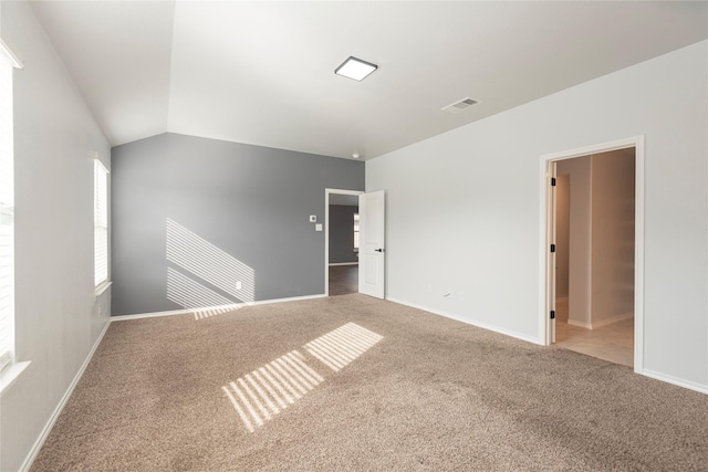 spare room featuring visible vents, lofted ceiling, baseboards, and carpet flooring