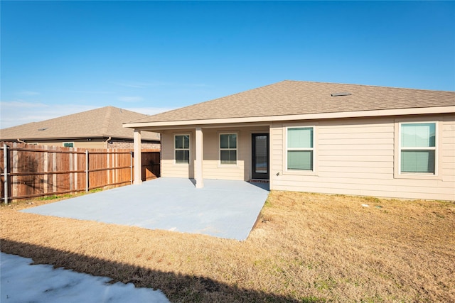 back of house featuring a lawn, roof with shingles, a patio, and fence