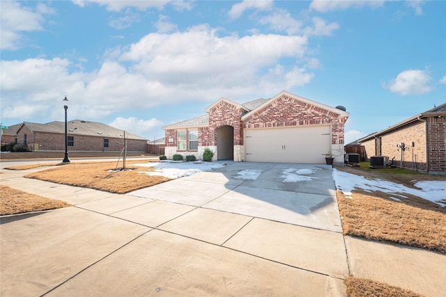 view of front facade with brick siding, central AC unit, driveway, and an attached garage