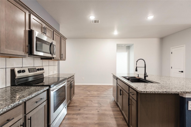 kitchen with light wood-type flooring, visible vents, a sink, tasteful backsplash, and stainless steel appliances