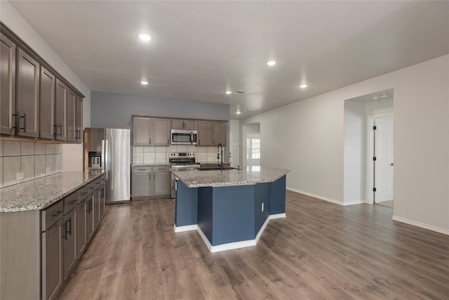 kitchen with dark wood finished floors, stainless steel appliances, tasteful backsplash, and a sink