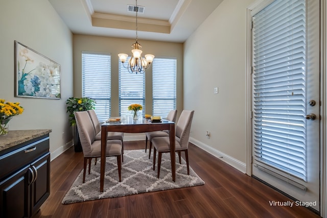 dining space featuring a tray ceiling, dark hardwood / wood-style flooring, ornamental molding, and a notable chandelier