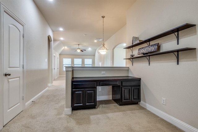 interior space featuring ceiling fan, light colored carpet, kitchen peninsula, and decorative light fixtures