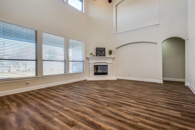 unfurnished living room with dark wood-type flooring and a high ceiling