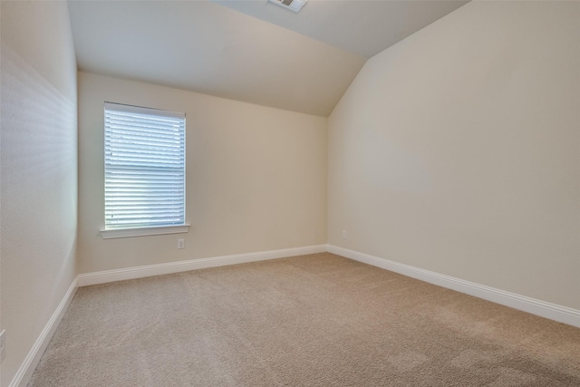 carpeted empty room featuring vaulted ceiling