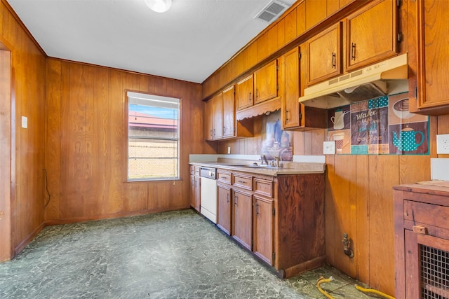 kitchen featuring white dishwasher, wood walls, and sink