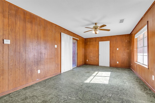 unfurnished room featuring ceiling fan and wooden walls